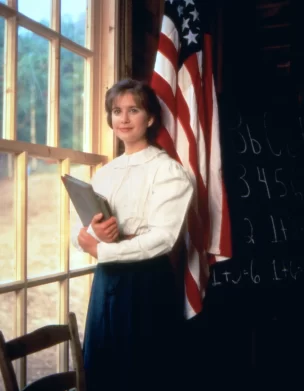 Christy Huddleston standing in schoolhouse with American Flag
