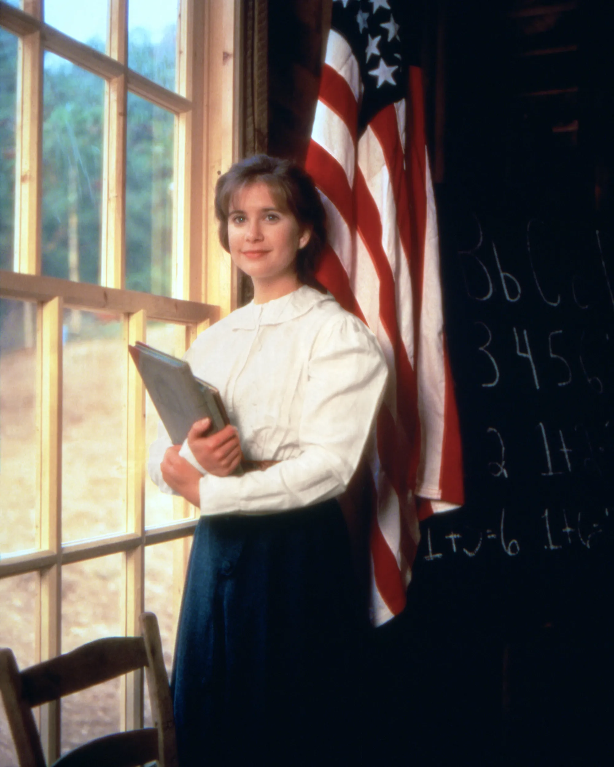 Christy Huddleston standing in schoolhouse with American Flag